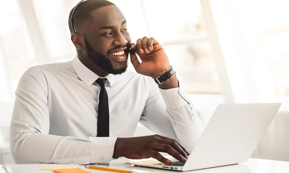 handsome-afro-american-businessman-suit-headset-is-talking-smiling-while-working-with-laptop-office