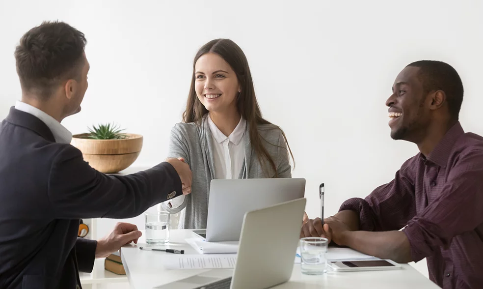 smiling-businesswoman-shaking-hand-male-partner-group-meeting