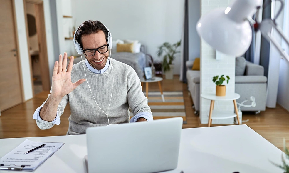 young-happy-businessman-waving-while-having-online-meeting-laptop-from-home young-happy-businessman-waving-while-having-online-meeting-laptop-from-home